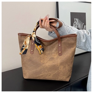 Close-up of brown vintage tote bag with decorative silk scarf and gold rivet detail