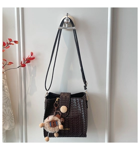 Detail of dark brown woven bucket bag with magnetic closure and cute sheep pendant