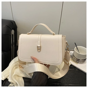 Detail view of cream white leather handbag with golden rectangular metal lock and wide strap