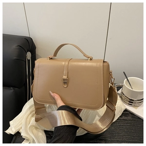 Detail of khaki faux leather handbag with golden metal clasp and wide fabric strap
