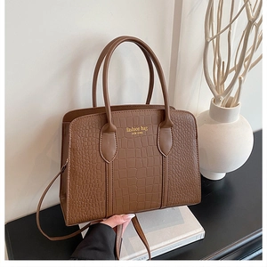 Macro detail of brown crocodile textured leather tote bag with gold logo lettering