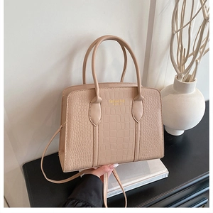 Detail of beige crocodile embossed tote bag with gold lettering and adjustable strap