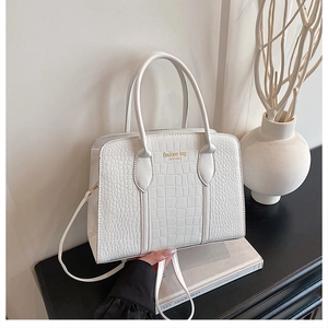 Detail of white crocodile pattern tote bag with gold lettering and adjustable strap