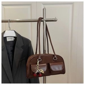 Detail of dark brown faux suede shoulder bag with dual pockets and cherry charm