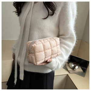 Detailed view of light pink quilted makeup bag with soft texture and metal zipper