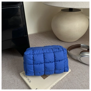 Detail of blue quilted puff makeup bag on magazine with modern home decor lifestyle scene