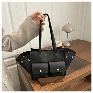 Detail of black pebbled leather tote bag with front snap pockets and gold fashion logo