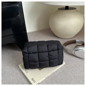 Detailed shot of a black quilted puffy cosmetic bag with smooth satin sheen and zip closure