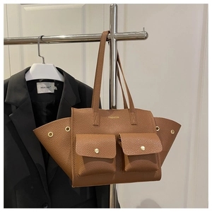 Detail of brown litchi pattern tote bag featuring dual front pockets and metal eyelets