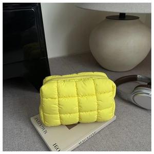Macro detail of yellow quilted cosmetic bag with grid texture and zipper closure