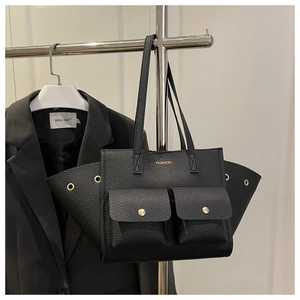 Detail of black pebbled leather tote bag with gold hardware and flap pockets