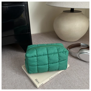 Detail of green quilted puffer cosmetic bag with soft texture and matching zipper