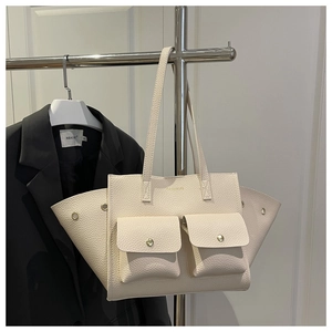 Detail of beige textured tote bag featuring double metal buckle front pockets