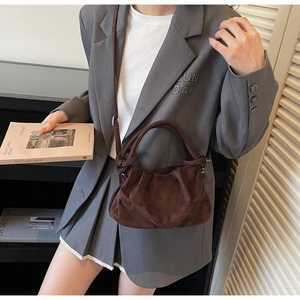 Detailed view of dark brown suede ruched cloud bag with knotted handle and strap