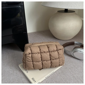 Close-up of a brown quilted makeup bag with square stitching on a white magazine