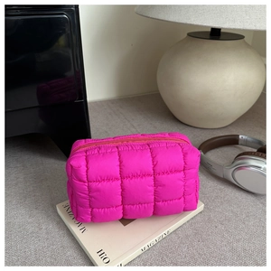 Detail of rose pink quilted puffer toiletry bag with top zipper and soft square texture