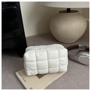 Close-up of white quilted cosmetic bag featuring soft texture and smooth zipper detail