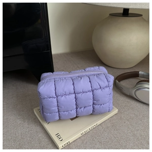 Detail of purple quilted fabric on a makeup bag with zipper closure in lifestyle setting