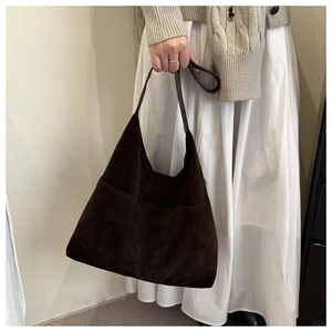 Close-up of a large brown suede tote bag with outer pocket on a shoulder strap