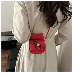 Détail du petit sac rouge avec nœud et broderie poney porté par une petite fille