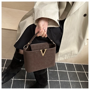 Detailed shot of dark brown matte handbag with signature gold V-shaped metal buckle