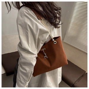Brown frosted leather tote bag with gold chain strap and deer pendant on female model