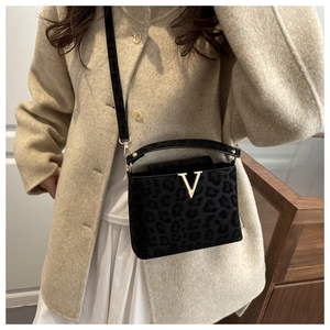 Detailed view of women's leopard print handbag with gold V clasp and leather strap