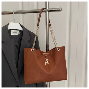 Detailed texture of brown corduroy tote bag with gold deer charm and chain strap