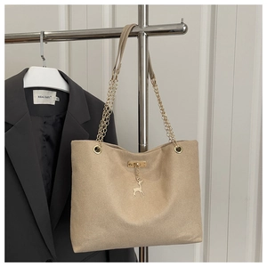 Detail of beige tote bag featuring golden deer charm and chic chain leather strap