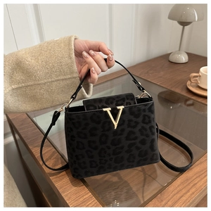 Close-up of black leopard print handbag with gold V-shaped metal clasp and suede texture