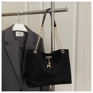 Close-up of black matte tote bag featuring gold deer charm and chain strap detail