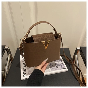 Detailed close-up of brown faux leather handbag with leopard print flap and gold V-clasp