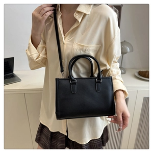 Close-up of black square bag with vertical stripe texture and detachable shoulder strap