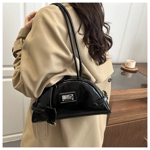 Glossy black crescent shoulder bag with metallic logo plate worn by model