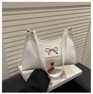 Detailed view of the white patent leather shoulder bag featuring a gold bow metallic buckle