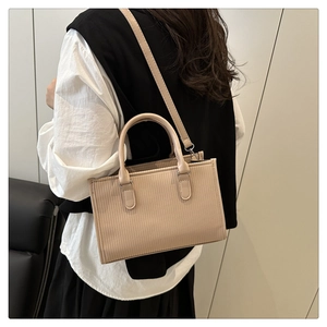 Apricot PU leather crossbody bag with vertical embossed texture shown on model