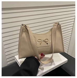 Detail of glossy beige patent leather underarm bag with gold bow knot and wide strap