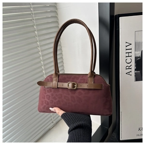 Detail of burgundy leopard print suede texture with brown leather straps and gold buckle