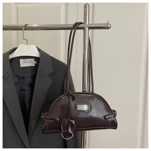 Detailed close-up of glossy dark brown bowling bag with metallic logo and sleek straps