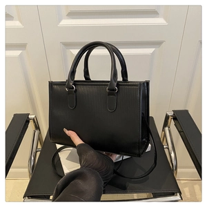 Close-up of black textured leather handbag with vertical embossed patterns and silver hardware