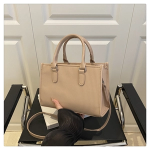 Detail of ribbed beige tote bag featuring sleek handles and a slim shoulder strap
