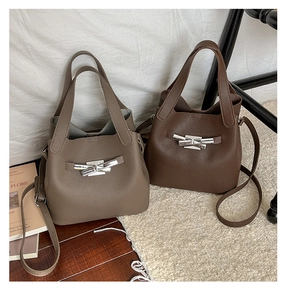Détail de sacs seau en cuir grainé taupe et marron avec fermoir métallique argenté