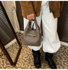 Gros plan du sac seau en cuir grainé taupe avec boucle de fermeture en métal argenté