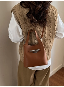 Sac seau en cuir marron avec fermoir rotatif argenté porté par un mannequin