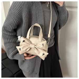Détail du sac à main beige avec nœud décoratif et clous argentés en étoile