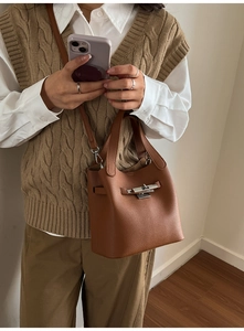Sac seau marron chic avec texture litchi et fermoir rotatif argenté en situation de style