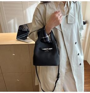 Détail du sac seau en cuir grainé noir avec fermoir rotatif argenté et bandoulière
