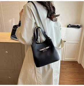 Détail du sac seau en cuir grainé noir avec fermoir rotatif argenté et bandoulière
