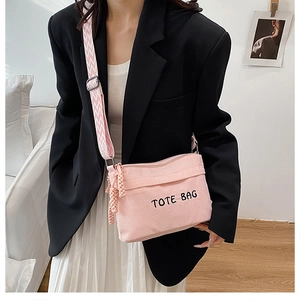 Gros plan du sac fourre-tout en velours côtelé rose avec broderie et bandoulière à motifs