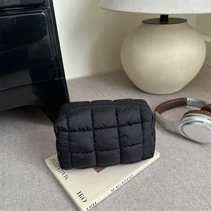 Quilted black makeup bag with a soft padded finish and zip closure for daily travel
